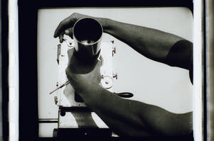 Kaufman schraubt Objektiv auf die Kamera, zwei Hände