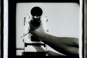 Kaufman schraubt Objektiv auf die Kamera, eine Hand