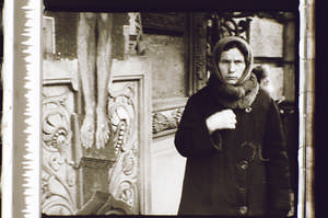 Frau bekreuzigt sich vor dem Kreuz, schaut direkt in die Kamera