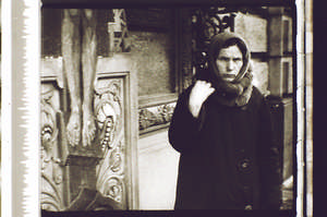 Frau bekreuzigt sich vor dem Kreuz, schaut in die Kamera